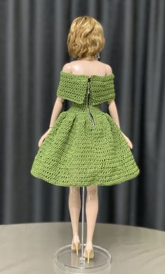 the doll is wearing a green crocheted dress