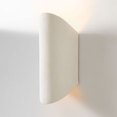 a white wall light mounted to the side of a wall with a curved corner on it