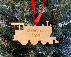 a wooden ornament hanging from a christmas tree with a train on it's side