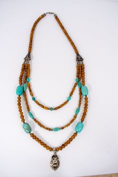 a multi strand necklace with turquoise beads and an elephant head pendant on it's end