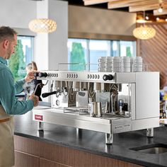 a man standing in front of a counter with a coffee machine on top of it