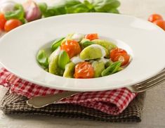 a white plate topped with salad on top of a red and white checkered cloth