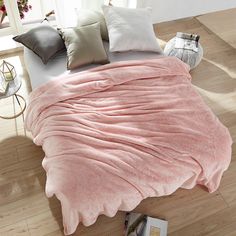 a bed covered in a pink blanket and pillows