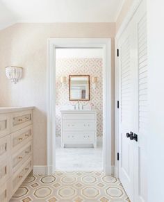 a white dresser sitting in a bathroom next to a mirror on a wall above it