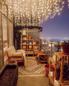 an apartment balcony with lights hanging from the ceiling and furniture on the floor, along with potted plants