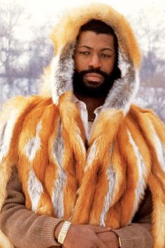 a man with a beard wearing a fur coat and holding his hands in his pockets