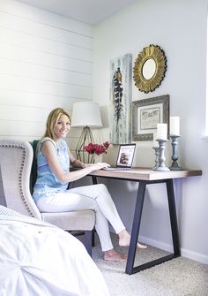 a woman sitting at a desk with a laptop in front of her on the bed