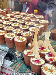 there are many desserts on the table with spoons in front of them and people standing around