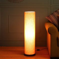 a floor lamp sitting on top of a hard wood floor next to a couch in a living room