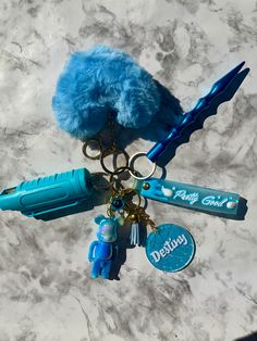 a blue keychain that has some items attached to it and is laying on a marble surface