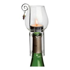 a wine bottle with a candle in it and a glass holder on the top that is holding grapes