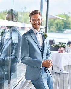 a man in a blue suit standing next to a window