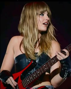 a woman holding a red guitar in her right hand