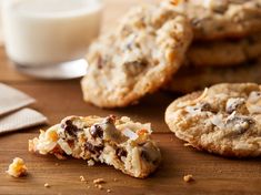 cookies and milk on a wooden table with one broken cookie in the foreground, another half eaten