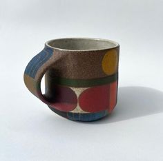 a coffee cup is sitting on a white surface with multicolored circles around it