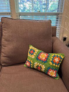 a brown chair with a colorful pillow on it