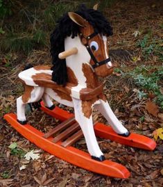 a toy rocking horse sitting on top of leaves