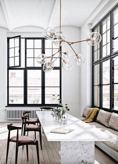 an elegant dining room with white walls and wood flooring, chandelier hanging from the ceiling