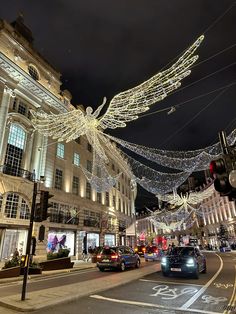 cars are driving down the street with christmas lights strung from it's sides and buildings in the background