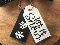 two black and white tags with snowflakes on them sitting on a wooden table