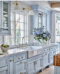 a kitchen with blue cabinets and marble counter tops, gold pulls on the faucets