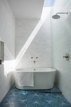 a white bath tub sitting next to a shower in a bathroom under a skylight