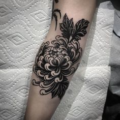 a black and white flower tattoo on the arm