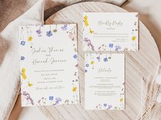 the wedding stationery is laid out on top of a wooden table with flowers and greenery