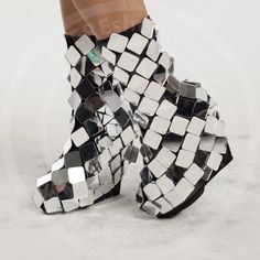 a woman's legs with mirrored cubes on the bottom, and heeled boots