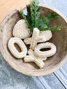 a wooden bowl with rope wrapped around it and a sprig of rosemary in the center