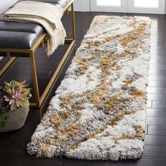 a white and yellow area rug on a wooden floor next to a bench with a plant