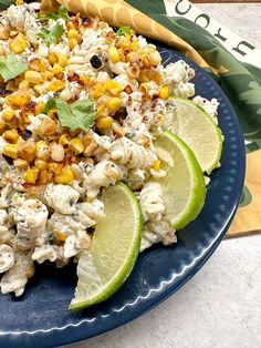 a blue plate topped with corn salad and lime wedges