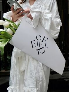 a woman in white dress holding a bag and cell phone