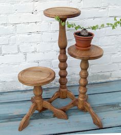 two wooden pedestals with plants in them sitting on a blue wood floor next to a white brick wall