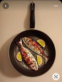 a pan with some fish in it on the wall next to a frying pan