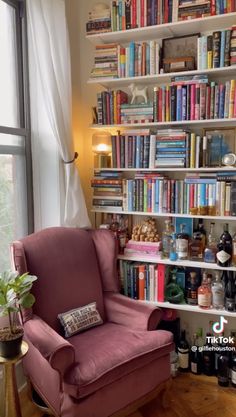 a chair in front of a book shelf filled with lots of books next to a window