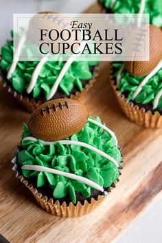 three cupcakes with green frosting and football decorations on top, sitting on a cutting board