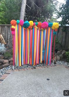 colorful paper pom poms and streamers are on the side of a fence