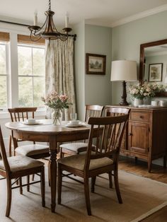 a dining room table with chairs and a chandelier in front of the window