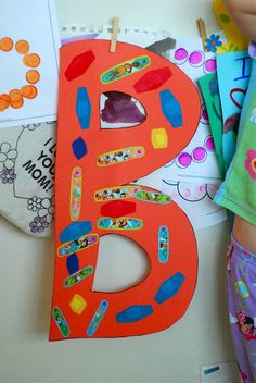 a child is holding up a paper letter that has been made to look like the number five