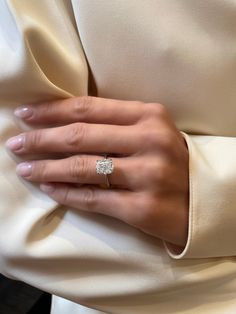 a woman's hand with a diamond ring on her left wrist, wearing a cream colored dress