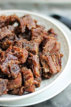 a white plate topped with sliced beef on top of a table next to a knife and fork