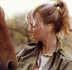 a woman standing next to a horse with her hair in a pony's bun