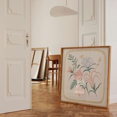 an empty room with two chairs and a painting on the floor in front of it