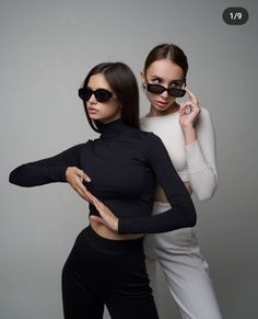 two beautiful women in black and white outfits posing for a photo with their arms around each other