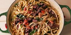 a pot filled with pasta and meat on top of a wooden table