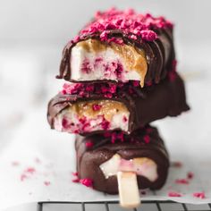 three chocolate covered ice cream pops with pink sprinkles