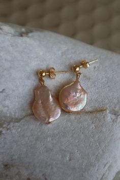 Dulcis - Sweet & Charming A peachy natural biwa pearl in a lovely drop shape hanging from a 24K gold plated round setting. The slightly asymmetrical pearls measures 1.5 x 2 cm and 1.3 x 1.7 cm and the total length of the earrings are 2.5 cm. Our jewelry comes in a stylish and safe packaging, ready to be gifted to a special person or to yourself. Handmade in Nitentia's studio in Stockholm, Sweden. We use all natural pearls and genuine gold plated settings. Please join Nitentia on Instagram for in Pear-shaped High Luster Pearl Earrings, Pear-shaped High Luster Pearl Earrings Gift, Gold Plated Teardrop Pearl Earrings, Gold-plated Teardrop Pearl Earrings, Handmade Gold Briolette Pearl Earrings, Rose Gold Teardrop Earrings With Pearl Charm, Gold Pear-shaped Pearl Pendant Earrings, Pear-shaped Gold Pearl Pendant Earrings, Gold Pear-shaped Pearl Charm Earrings