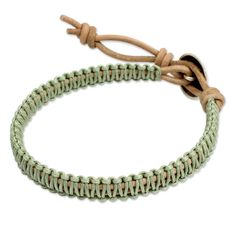 a green and beige bracelet on a white background with a knot at the end of it