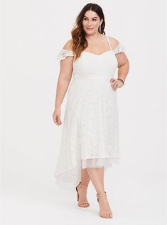 a woman in a white dress posing for the camera with her hands on her hips